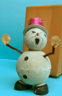 34: 19cm high snowman container with hands mounted on springs. The head comes off at the neck, revealing the container. Possibly with its original box, although it seems too small; on the side is stamped ‘7020’ and ‘24’ and in pencil “Blanc” (white)